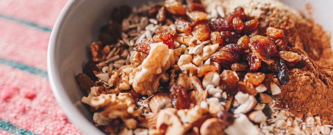 Bol de frutos secos, semillas y pasas, superalimentos ricos en antioxidantes y vitaminas que mejoran la salud y luminosidad de la piel.