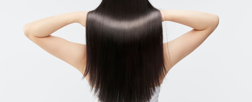 Cabello largo, liso y saludable de mujer tras tratamiento contra la ca&iacute;da capilar, ejemplo de recuperaci&oacute;n de densidad y brillo.